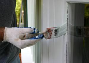 Putting on a second coating of paint on a Sherman home